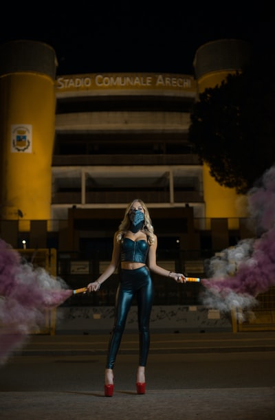 女人站在人行道上在夜间举行烟幕弹
